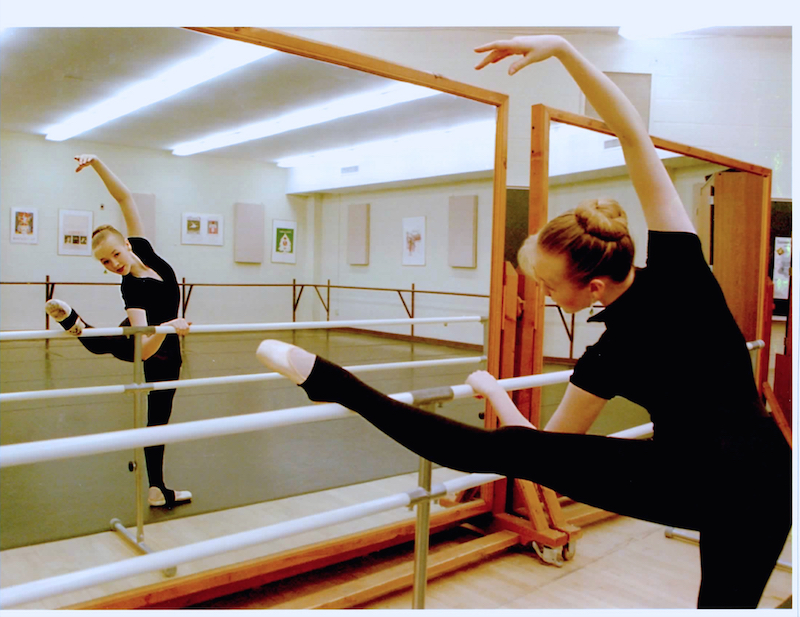 Michelle Loucadoux as a student stretching her leg on the bar